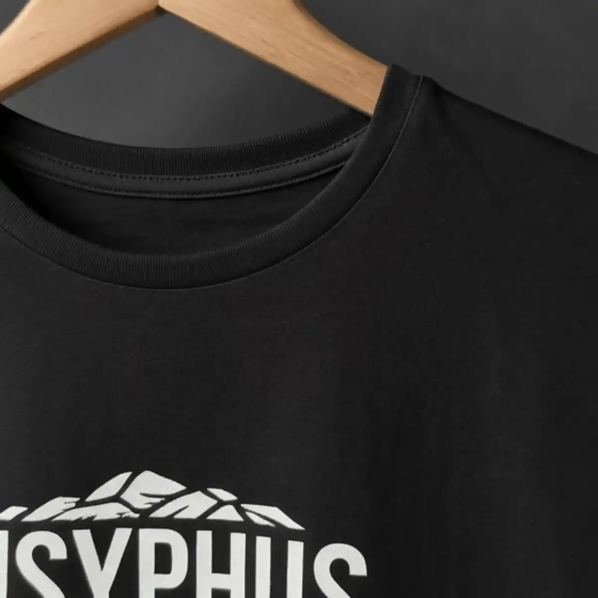 Camiseta Sísifo – Filosofia | Silk & Luck 6 Foco na gola com costura reforçada de camiseta preta em cabide de madeira com a tipografia Sisyphus em branco.